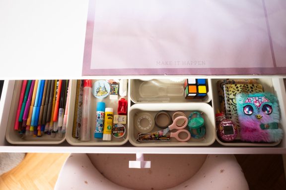 Tiroir avec fournitures de bureau : crayons, ciseaux, colle et agenda coloré.